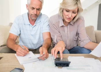 Senior couple with papers and calculator at home | FintechZoom