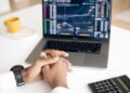 Person Using Laptop to trading on market | FintechZoom