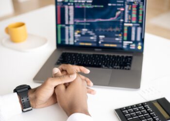 Person Using Laptop to trading on market | FintechZoom