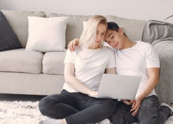 Man And Woman In White Crew Neck Shirt Looking At A Laptop | FintechZoom