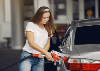 Focused young woman refueling car | FintechZoom