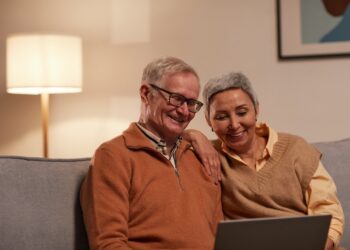 Man and Woman Sitting on Sofa While Looking at a Laptop | FintechZoom