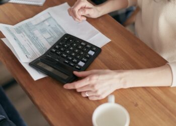 Woman with calculator and bills | FintechZoom