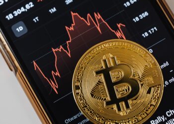 A Gold BitCoin on a Smartphone Screen | FintechZoom