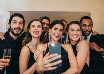 Woman with friends taking selfie at a gala night event. Multi-ethnic group of people making a selfie at a Gala Night | FintechZoom