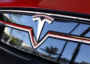 Tesla Logo in red car | FintechZoom