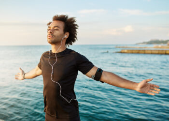 Healthy afro-american man stretching his arms before outdoor workout | FintechZoom
