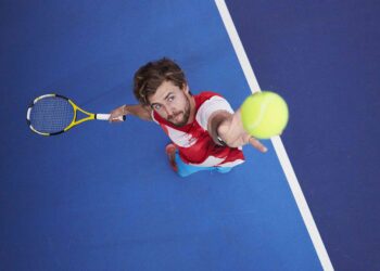 Tennis player hitting a serve | FintechZoom