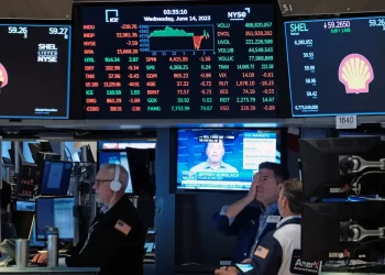 Traders on the floor of the New York Stock Exchange monitor market activity. Multiple screens display stock information, with red and green indicators showing market performance. The date on the screen reads Wednesday, June 14, 2023. | FintechZoom