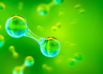 A 3D rendering of a molecule, resembling two spherical atoms connected by a rod, set against a vibrant green background. Smaller identical molecules can be seen in the background, giving a sense of depth and scale, akin to visualizing the promising future of Green Hydrogen Stocks. | FintechZoom