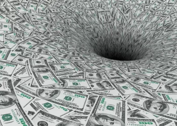 Hundred-dollar bills arranged in a way that creates a visual effect of them spiraling into a deep, dark hole in the center, evoking hyperinflation's impact. The imagery suggests the concept of money being lost or disappearing into a void. | FintechZoom