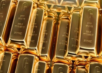 A stack of shiny gold bars, each labeled with "5000 grams," "999.9 fine gold," and a serial number, fills the frame. The bars have a rich, golden hue and appear tightly packed together, reflecting light to highlight their glossy surfaces—ideal for a 401(k) Gold Rollover investment strategy. | FintechZoom