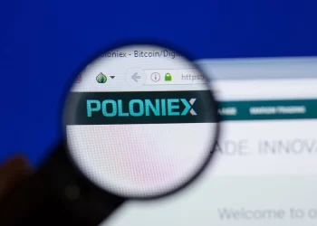 A magnifying glass hovering over a computer screen displays the Poloniex website, highlighting the logo. The browser tab shows the URL "Poloniex Hacked" as a reminder of past vulnerabilities, and the background is slightly blurred and predominantly blue. | FintechZoom