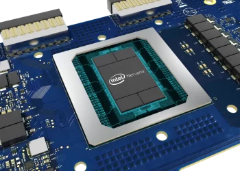 Close-up of an Intel Nervana processor chip on a blue circuit board. The chip sits at the center, displaying the Intel logo, symbolizing innovation. The circuit board features various electronic components, including capacitors and connectors, arranged around the processor—an asset to consider for Intel stock enthusiasts. | FintechZoom