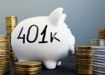 A white piggy bank with "401k" written on its side is placed amidst numerous stacks of coins, symbolizing financial savings and retirement funds. The background is a gradient of light to dark blue, emphasizing the importance of understanding the max contribution to 401k for securing your future. | FintechZoom