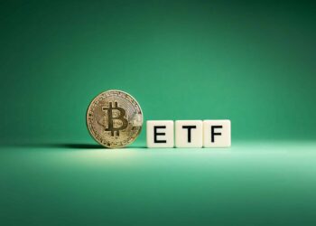 A physical representation of a Bitcoin stands next to three white blocks with black letters spelling "ETF" on a green background, hinting at the anticipated Bitcoin ETF 2024. | FintechZoom