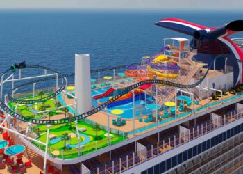 Aerial view of a Carnival stock cruise ship's deck featuring a vibrant waterpark with colorful slides, a large pool, mini-golf course, and a roller coaster track. The deck has multiple lounging areas with blue and red tables and chairs, all set against a backdrop of the ocean. | FintechZoom