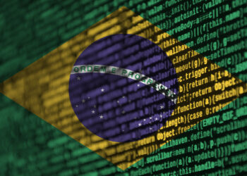 The Brazilian flag is superimposed over a background of green computer code, symbolizing Brazil’s iGaming evolution. The flag features a yellow diamond with a blue globe containing stars and a banner with the national motto "Ordem e Progresso" ("Order and Progress"). | FintechZoom