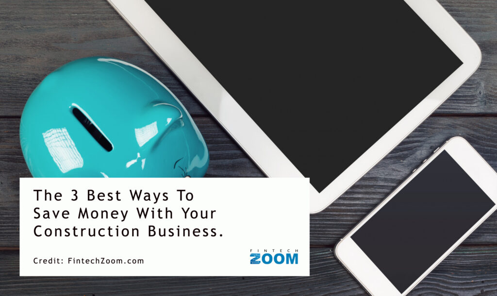 A teal piggy bank, a tablet, and a smartphone sit on a wooden table. A white card displays the text, "The 3 Best Ways To Save Money With Your Construction Business." Credit: FintechZoom.com. | FintechZoom