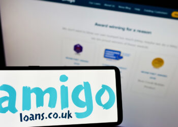A smartphone displays the "Amigo Loans" logo with the website's awards and accolades section visible in the background. The site features a dark navigation bar at the top and showcases various award badges. | FintechZoom