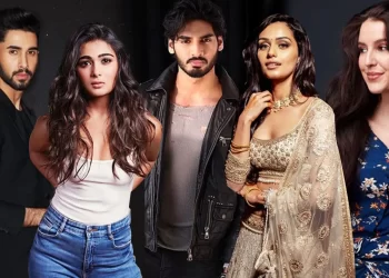 A group of five people stands together against a dark background, embodying the allure of Moviesming. Two men and three women pose confidently in fashionable attire, including casual wear, a leather jacket, and traditional clothing. All have serious or neutral expressions. | FintechZoom