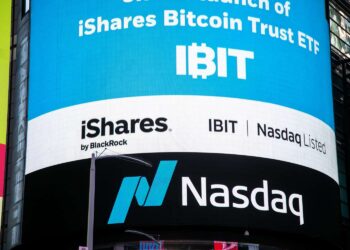 A large digital billboard displays the launch of BlackRock Spot Bitcoin ETF by iShares, with text highlighting "IBIT" and Nasdaq listing. The Nasdaq logo is prominently shown at the bottom of the billboard. | FintechZoom