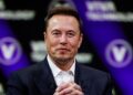 A man in a dark suit and white shirt is pictured in front of a black and purple backdrop with the text "Viva Technology." He sits with his hands clasped, looking straight ahead with a slight smile, reminiscent of the calm seen in photos of Elon Musk at his house. | FintechZoom