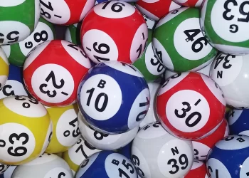 A pile of colorful bingo balls with various numbers and letters printed on them resembles the excitement found on Dpboss Net. The balls are red, blue, green, yellow, and white, featuring numbers from single to double digits and letters like B, N, O, and G. | FintechZoom