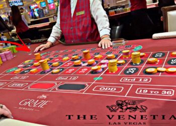 Image of a casino roulette table at The Venetian Las Vegas, with stacked chips on various numbers. A dealer, wearing a red vest and white shirt, is managing the game while other players’ hands with chips can be seen at the table’s edge, capturing the vibrant essence of iGaming. | FintechZoom
