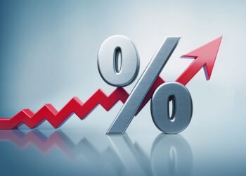 A large metallic percentage symbol rests against a red, upward-trending arrow on a light blue background, indicating an increase or growth in prime rate percentages. | FintechZoom