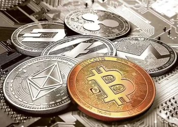 A collection of various cryptocurrency coins is displayed on top of a computer motherboard. The coins, including Bitcoin, Ethereum, Ripple, Litecoin, and Monero, each showcase their unique symbols and designs. The background features intricate circuitry elements reminiscent of the dynamic world of fintech and the cutting-edge insights from FintechZoom. | FintechZoom