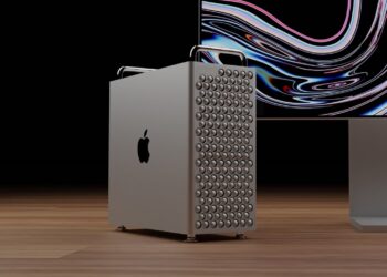 A sleek, silver computer tower with a distinctive lattice grill design stands on a wooden surface. It features the iconic Apple logo, signifying it as a Mac product, and is partially overshadowed by a modern monitor displaying colorful, wavy lines on a dark background. | FintechZoom