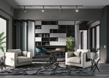 A modern living room by Henry Dannell features two white armchairs facing each other, separated by a small glass coffee table with a potted plant. Behind the chairs, there's a decorative rug and a home office with bookshelves and a desk. Large windows illuminate the space with natural light. | FintechZoom