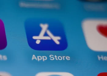 Close-up of a smartphone screen showing the App Store icon, with a blue background featuring a stylized white A made from painting tools. Other partially visible app icons are blurred in the background, reminiscent of Apple Stock imagery. | FintechZoom