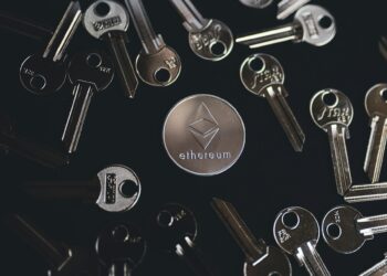 A silver Ethereum token surrounded by multiple shiny metallic house keys on a black background. | FintechZoom