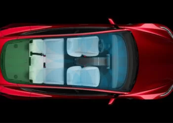A top view of a red car with a transparent roof, showing the interior seating arrangement. There are two front seats, two rear seats, and additional space in the back. The seats are white, and the car's exterior is a vibrant red. The dashboard is visible, reminiscent of the sleek design you’d expect from Tesla stock offerings. | FintechZoom