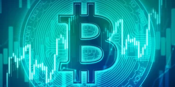 A glowing blue Bitcoin logo is prominently displayed in the center of the image against a background of rising and falling stock market charts. The image symbolizes the fluctuations in the value of Bitcoin, hinting at potential trends of Bitcoin going up among other cryptocurrencies. | FintechZoom