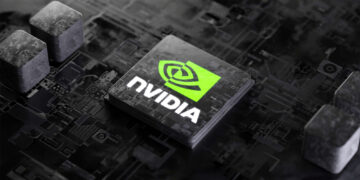 A close-up image of an Nvidia semiconductor amid a dark circuit board. The prominent Nvidia logo, featuring a green eye symbol and bold white text, is clearly displayed on the chip. Surrounding components and intricate circuitry are visible in the background. | FintechZoom