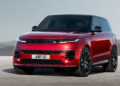 A vibrant red Range Rover SUV, possibly the best hybrid SUV on the market, is parked on a plain concrete surface, set against a backdrop of hazy mountains and a clear sky. The vehicle features sleek, modern design elements with black detailing around the windows, grille, and wheels. The license plate reads "ABF 112. | FintechZoom