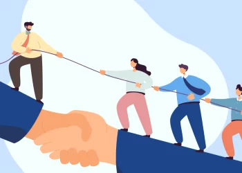 Illustration of four people pulling on a rope, seemingly in a tug-of-war. They are depicted standing on an enlarged handshake, symbolizing team building activities and unity. The background is a light blue with abstract shapes. | FintechZoom