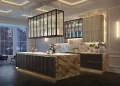 A luxurious modern kitchen with marble countertops and island, a glass rack above the island, and sleek dark wood cabinets. The room features elegant lighting, glass kitchen splashbacks, a large window with a tranquil view, and a cozy seating area with an armchair in the corner. | FintechZoom