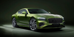 A sleek green luxury sports car, the new Bentley Continental GT, is parked on a smooth surface against a dark green background. It has a distinctive front grille, stylish headlamps, and large silver alloy wheels. | FintechZoom