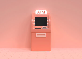 A pink ATM stands against a matching pink background. The machine has a screen, keypad, and card slot, with a sign on top that reads "ATM" illuminated in white. The floor consists of hexagonal tiles in a lighter shade of pink. | FintechZoom