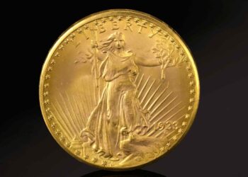 A close-up of a rare gold coin featuring Lady Liberty holding a torch and an olive branch, with rays extending behind her. The top of the coin reads "LIBERTY," and the year “1933” is inscribed at the bottom. The coin is surrounded by a border of stars. | FintechZoom