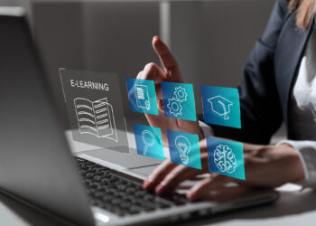 A person interacts with a laptop, selecting virtual icons representing various learning modules. The icons include an open book labeled "E-LEARNING," a document, gears, a graduation cap, a magnifying glass, a light bulb, and a brain—all seamlessly integrated into the Extended Enterprise Learning Management System. | FintechZoom