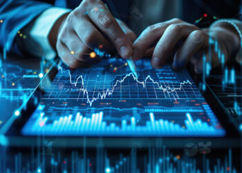 A close-up of hands holding a stylus over a digital tablet displaying a financial graph with rising and falling lines, indicative of market analysis or stock trading. The scene is set in a professional environment with a futuristic, digital interface overlay, reminiscent of FintechZoom.com Pro insights. | FintechZoom