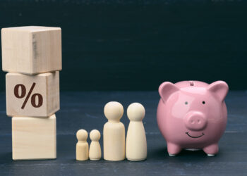 Wooden blocks with a percentage symbol, highlighting 6% CD rates, are stacked on the left. Wooden figures of a family stand in the middle, and a pink piggy bank sits on the right, all set against a dark background. | FintechZoom