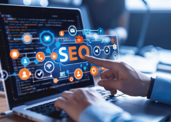 A person points at a digital interface labeled "SEO" on a laptop screen displaying lines of code, illustrating the impact of SEO and domain names on fintech digital growth. Icons representing internet and social media encircle the "SEO" text. | FintechZoom