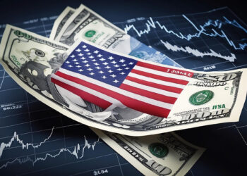A close-up of several U.S. hundred-dollar bills arranged in a fan shape, with a small American flag overlay and the backdrop of a volatile financial chart. This image evokes themes tied to the bond market today and economic fluctuations. | FintechZoom