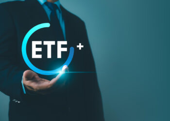 A person in a suit holds a glowing blue circle with the text "ETF+" inside, symbolizing financial or investment opportunities related to Exchange-Traded Funds. Set against a gradient of dark teal to light teal, this scene evokes the dynamic synergy between FintechZoom.com and Crypto ETF innovations. | FintechZoom
